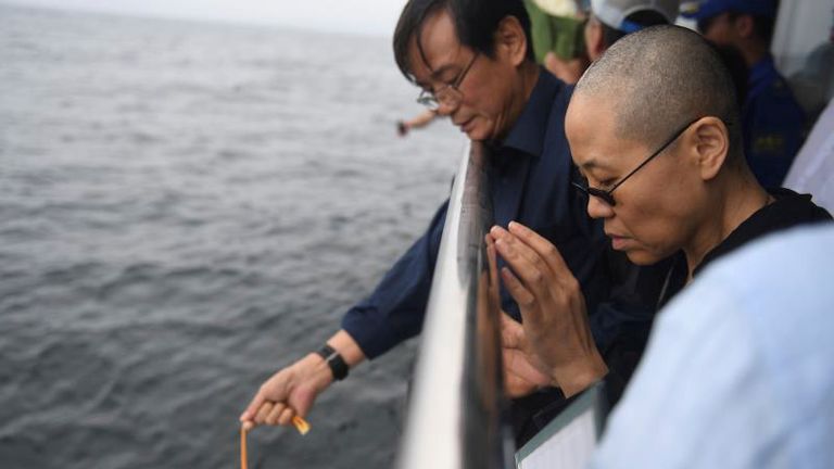 Ms Liu and other relatives lower the ashes into the sea