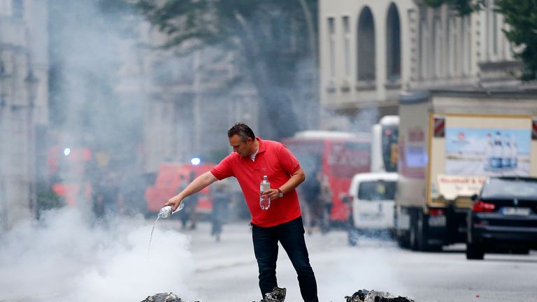 A man pours water over a burnt rubbish bin