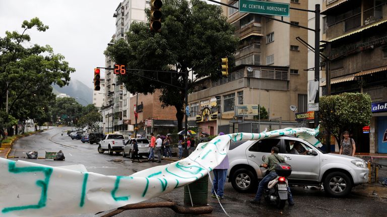 A car and a motorcyclist pass through a barricade 