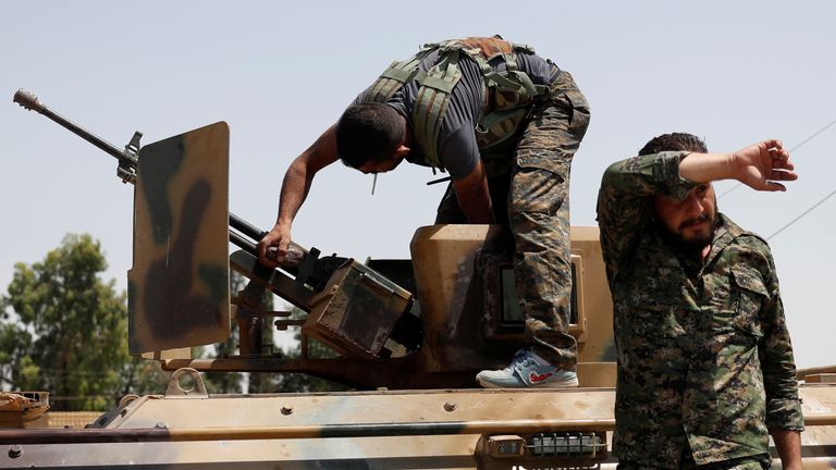 A Kurdish fighter from the People&#39;s Protection Units (YPG) adjusts a gun on top of an armored vehicle in Raqqa