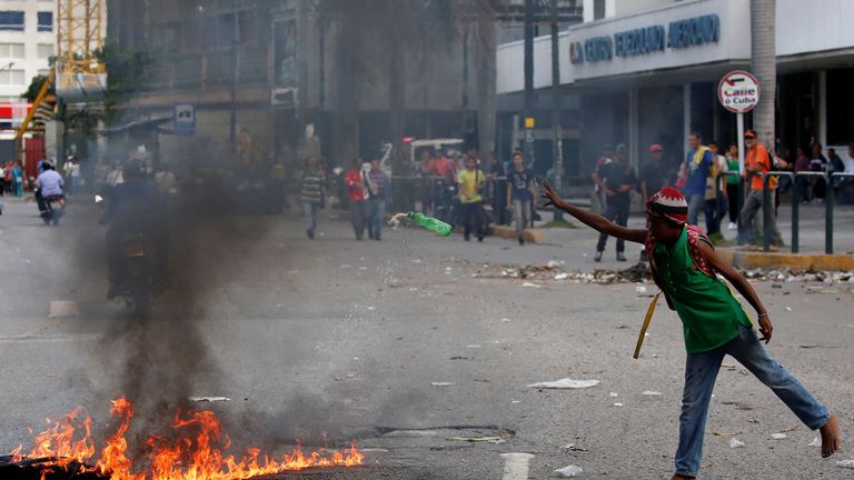 A barefoot man throws a bottle on a barricade 