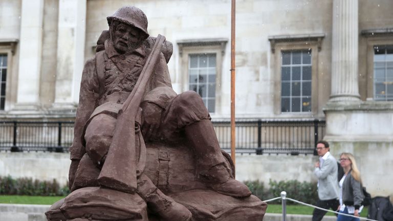Artificial rain falls on the 'Mud Soldier' statue, which is sculpted from sand and mud from Passchendaele, on the North Terrace of Trafalgar Square 