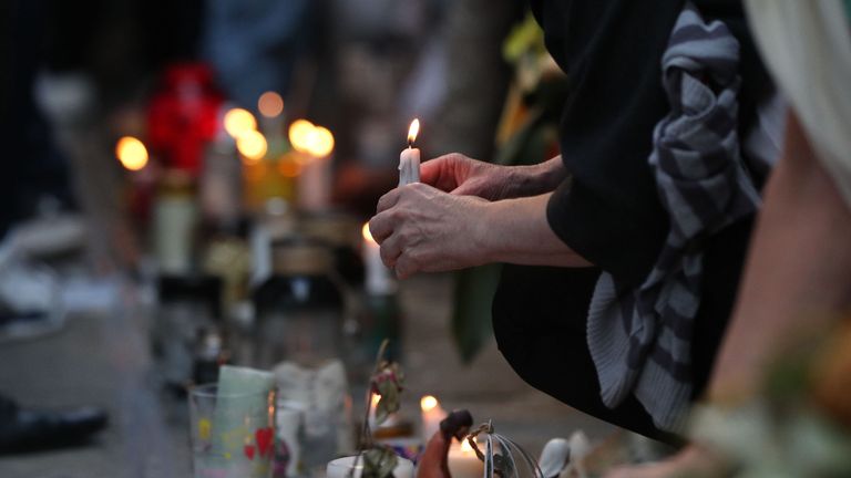 People place candles at the memorial wall on Bramley Road