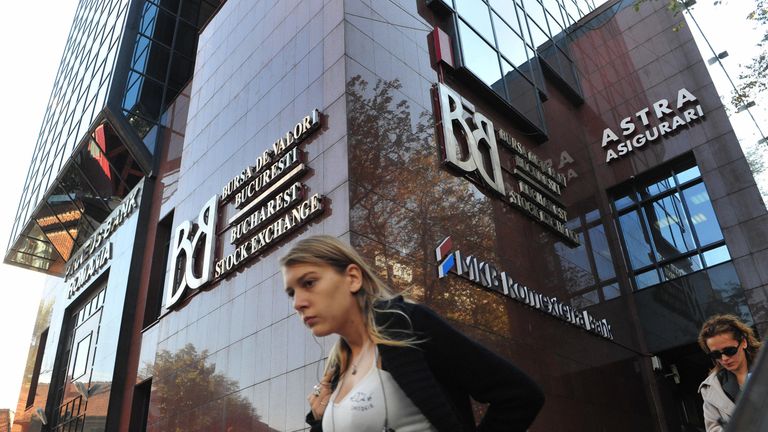 People walk past the Bucharest stock exchange headquarters in Bucharest on October 08, 2008. 