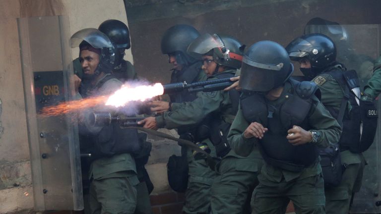 A riot security force member fires his weapon