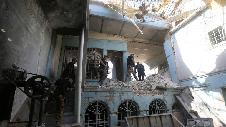 Iraqi Counter Terrorism Service personnel walk in a destroyed building 