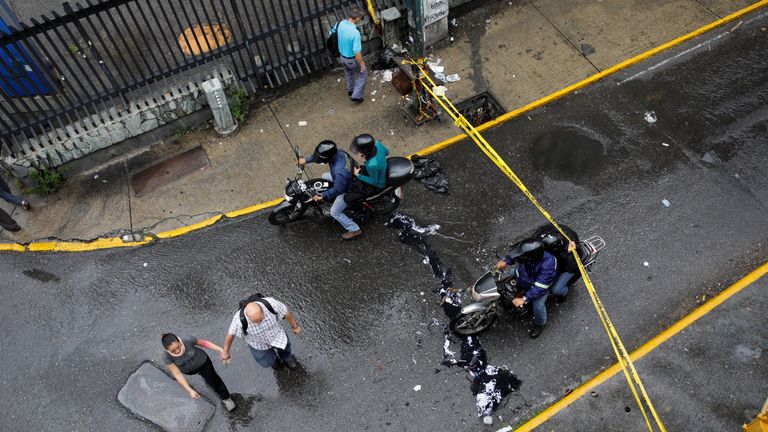 Pedestrians and a motorcyclist pass through a barricade 