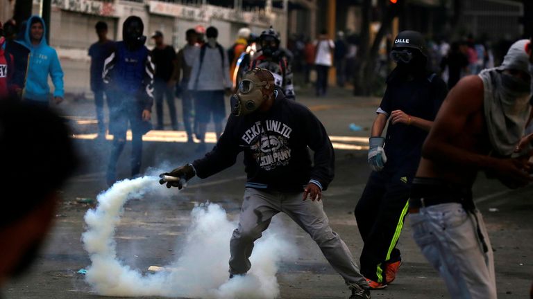 A demonstrator prepares to throw tear gas