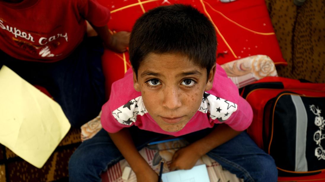 A displaced child from the Islamic State (IS) group's Syrian stronghold of Raqqa, poses for a photo as he attends the first day of the new school year at a camp for internally displaced people in Ain Issa on August 22, 2017