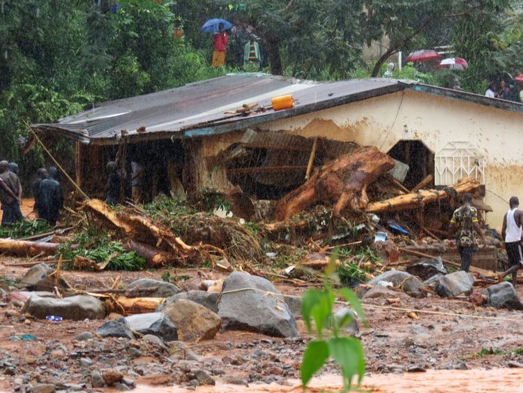 TOPSHOT - Bystanders and rescue personnel gather beside a flood damaged building in an area of Freetown on August 14, 2017, after landslides struck the capital of the west African state of Sierra Leone. At least 312 people were killed and more than 2,000 left homeless when heavy flooding hit Sierra Leone&#39;s capital of Freetown, leaving morgues overflowing and residents desperately searching for loved ones. An AFP journalist at the scene saw bodies being carried away and houses submerged in two ar