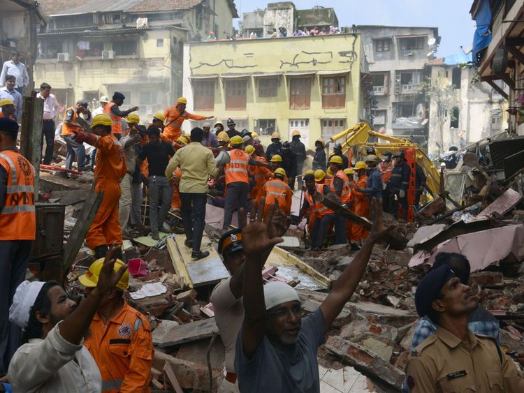 Rescue workers and residents look for survivors at the site of a building collapse in Mumbai 