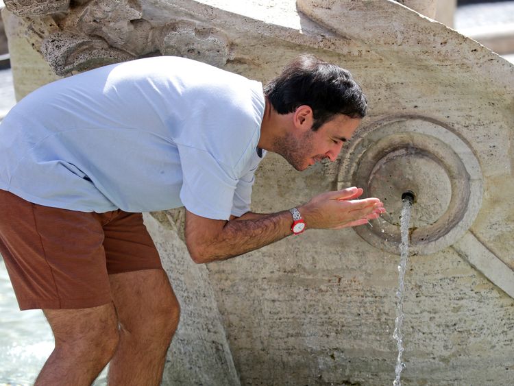 A man cools off by a fountain in downtown Rome
