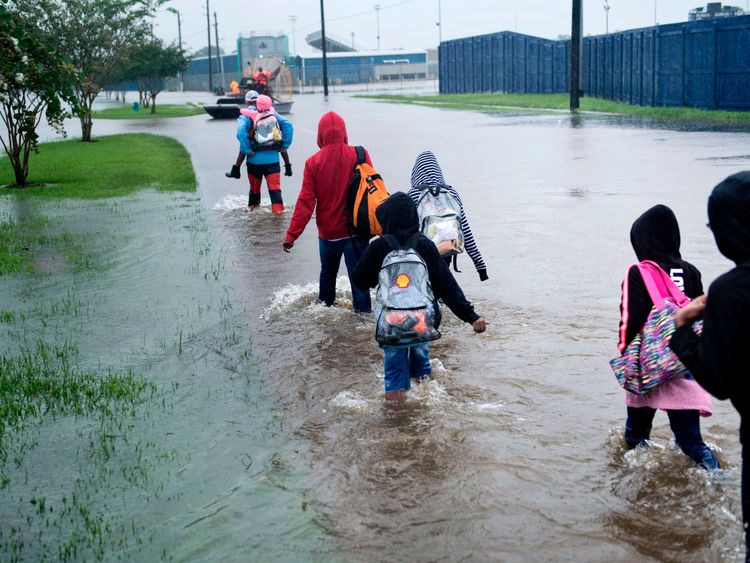 People walking towards an air boat to be rescued in Houston