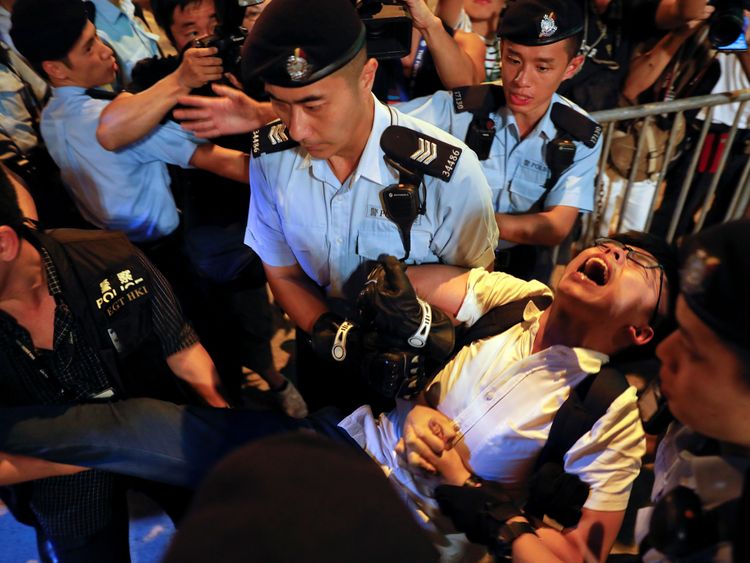 Joshua Wong shouts as he is carried by policemen during a protest