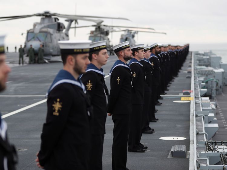 Sailors stand in line as the ship sails into harbour