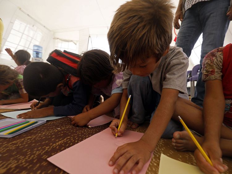 Displaced children from the Islamic State (IS) group's Syrian stronghold of Raqqa, attend the first day of the new school year at a camp for internally displaced people in Ain Issa on August 22, 2017