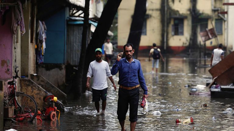 People walk through a partially flooded street at a residential area in Mumbai