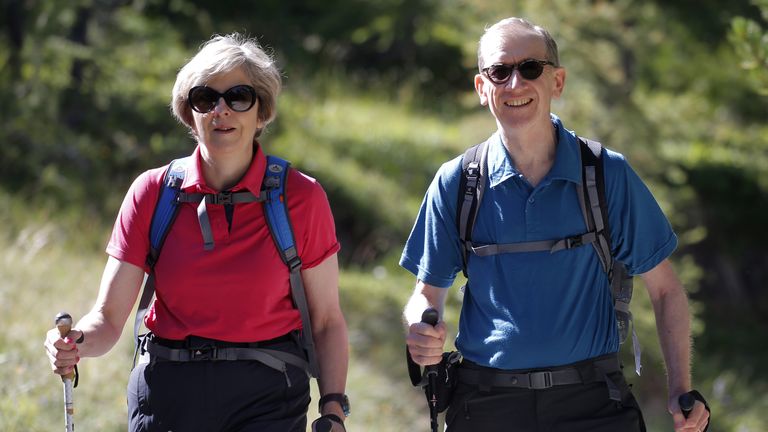 British Prime Minister Theresa May walks with her husband Philip John May while on summer holiday on August 12, 2016 in the Alps of Switzerland