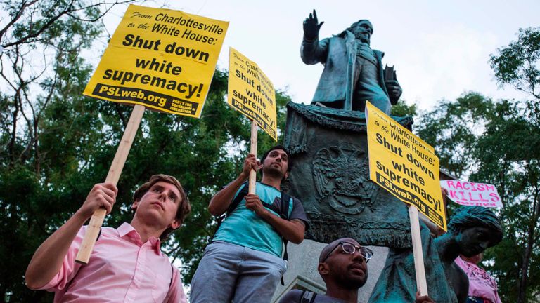 Demonstrators hold signs while standing in front of the statue of Confederate General Albert Pike on August 13, 2017 in Washington, DC, the only member of the Confederate military with an outdoor statue in the US capital, during a vigil in response to the death of a counter-protestor in the August 12 &#39;Unite the Right&#39; in Charlottesville, Virginia