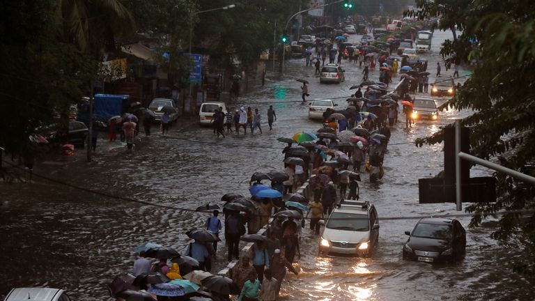 Commuters walk through water-logged roads after rains in Mumbai