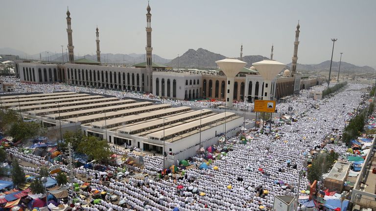 Muslim worshippers, some carrying umbrellas to protect them from the scorching sun, gather for prayer at Namirah mosque 