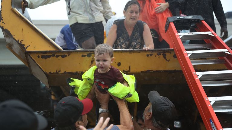 A young child is helped off the back of a rescue truck 