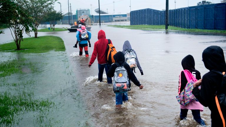 People walking towards an air boat to be rescued in Houston