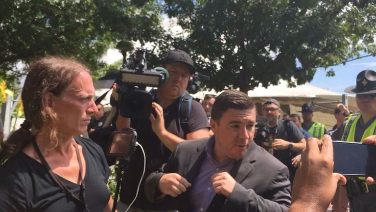 Jason Kessler was heckled and had to be rushed away when protestors stormed the podium.
