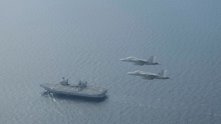 Two US Navy jets fly in formation above HMS Queen Elizabeth during an exercise 
