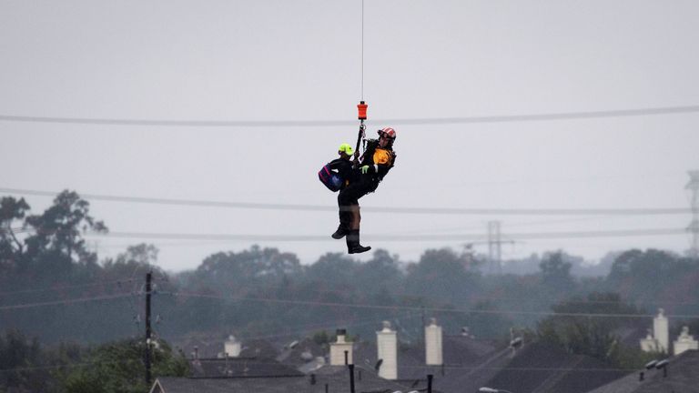 A Houston resident is winched to safety by a military helicopter