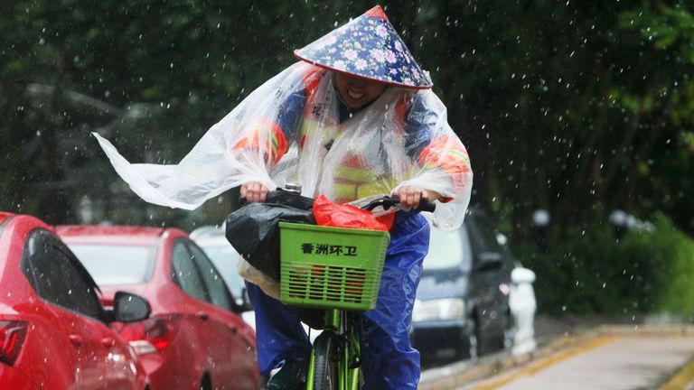 A sanitation worker rides a bicycle against the strong wind caused by Typhoon Hato on a road in Zhuhai in China&#39;s southern Guangdong province