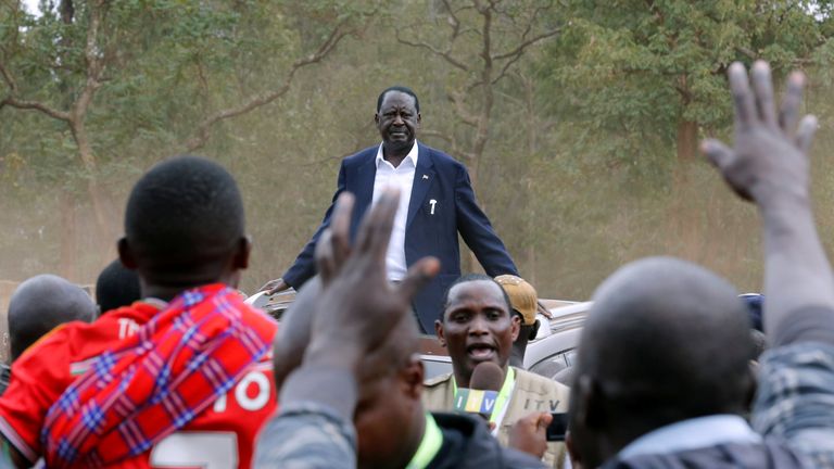 Opposition leader Raila Odinga stands atop of a vehicle outside the Kiberia slums of Nairobi after voting 