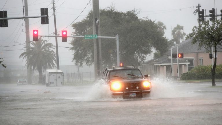 A vehicle navigates a street flooded by rain in Galveston, Texas