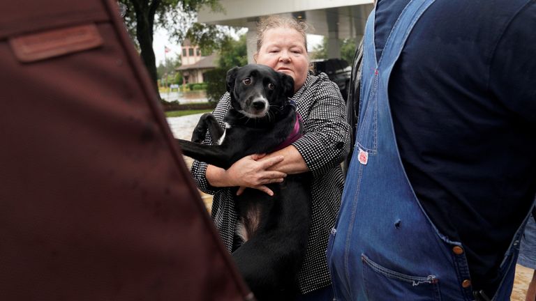 A woman carries her dog as she flees from the rising waters in the city of Dickinson