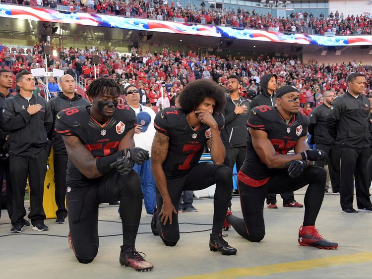 Colin Kaepernick (C), Eric Reid (R) and Eli Harold (L) kneel in protest during the national anthem in October 2016