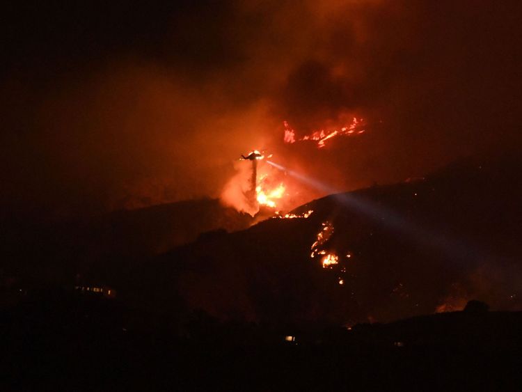 A helicopter drops water on the La Tuna Canyon fire at night in the hills above Burbank, California, early September 2, 2017. The brush fire which quickly burned 2,000 acres started on September 1 and was being driven by heat wave temperatures and high winds