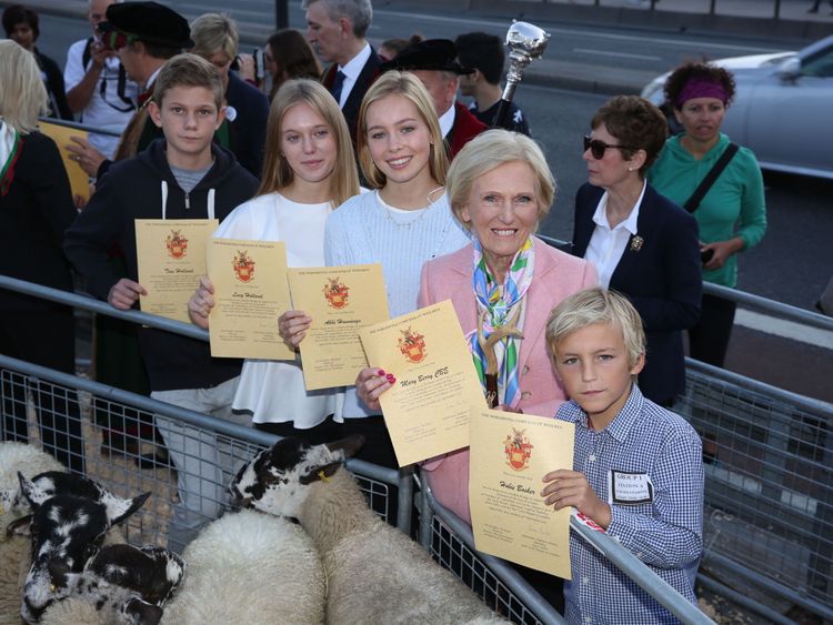 Celebrity baker Mary Berry holds her certificate with participants after herding sheep over London Bridge to help open the Wool Fair