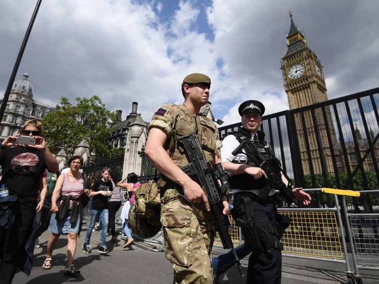 Armed soldier and armed police officer patrol outside Westminster Palace
