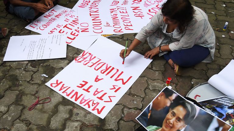 An student writes posters for a rally to protest the treatment of Rohingya Muslims in Myanmar, next to a picture of Myanmar&#39;s civilian leader and Nobel laureate Aung San Suu Kyi
