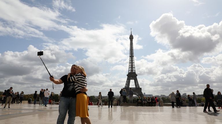 A couple take a selfie in front of the Eiffel tower in Paris