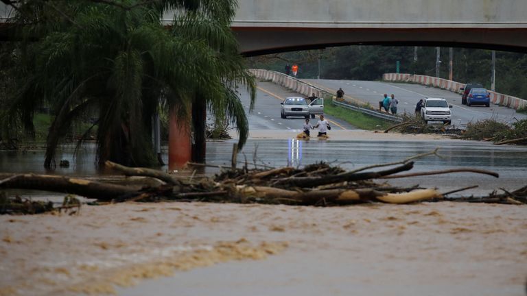 People wade through a flooded expressway in Yauco, Puerto Rico 