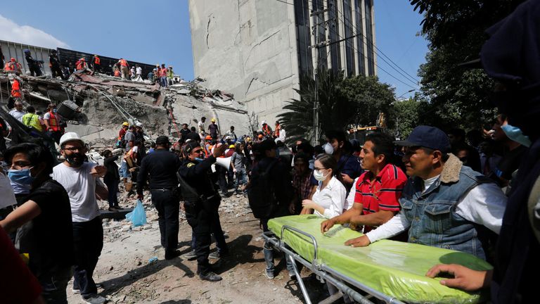 Paramedics wait as rescue personnel search for people in the rubble