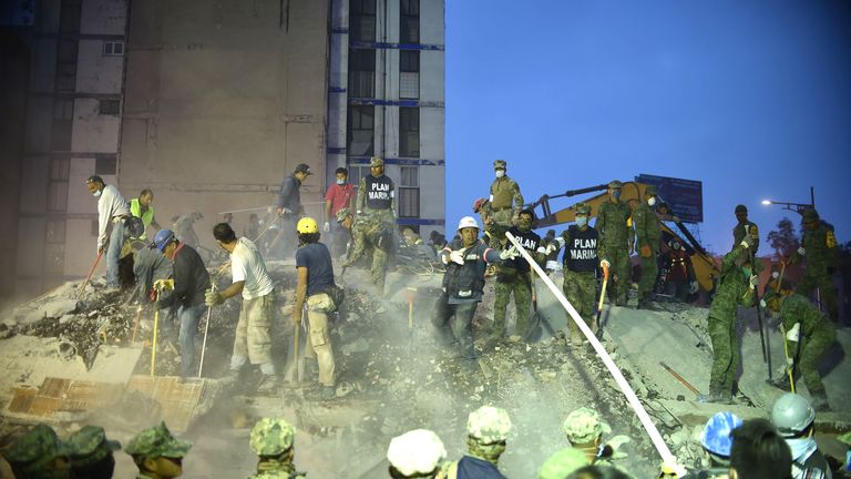 Rescuers, firefighters, policemen, soldiers and volunteers remove rubble and debris from a flattened building