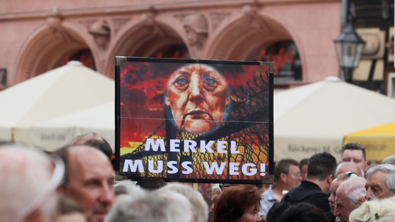 Protesters hold a sign reading &#39;Merkel must go&#39;
