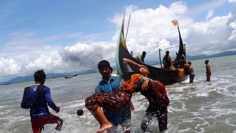 An exhausted Rohingya refugee woman is carried to the shore after crossing the Bangladesh-Myanmar border by boat through the Bay of Bengal