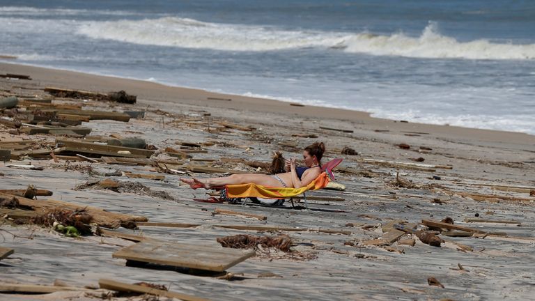 A woman sunbathes amongst debris on the beach after Hurricane Irma passed the area in Ponte Vedra Beach, Florida