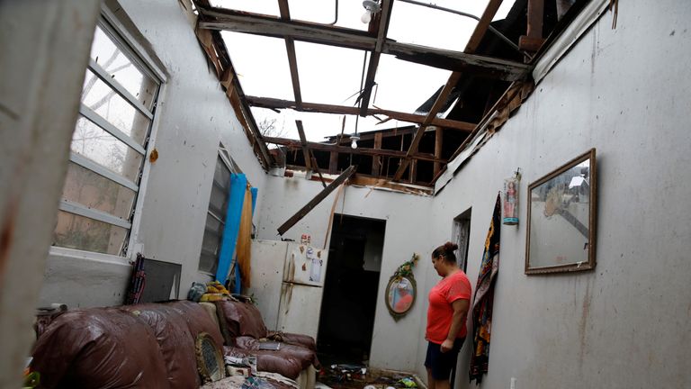 A woman looks at the damages in the neighbour&#39;s house after the area was hit by Hurricane Maria in Salinas, Puerto Rico, September 21, 2017