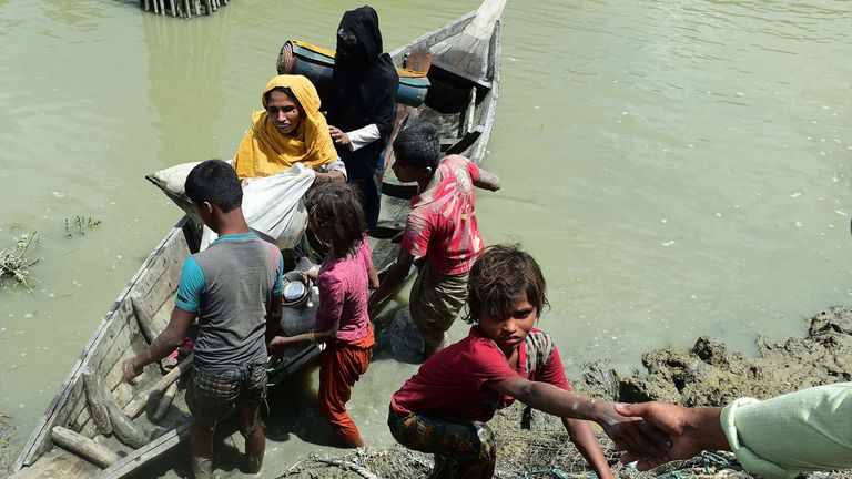 Local Bangladeshis help Rohingya Muslim refugees to disembark from a boat on the Bangladeshi side of Naf river near the Bangladeshi town of Teknaf