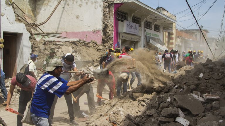 Volunteers clean the debris from damaged houses in Jojutla de Juarez on September 20, 2017 a day after a strong quake hit central Mexico