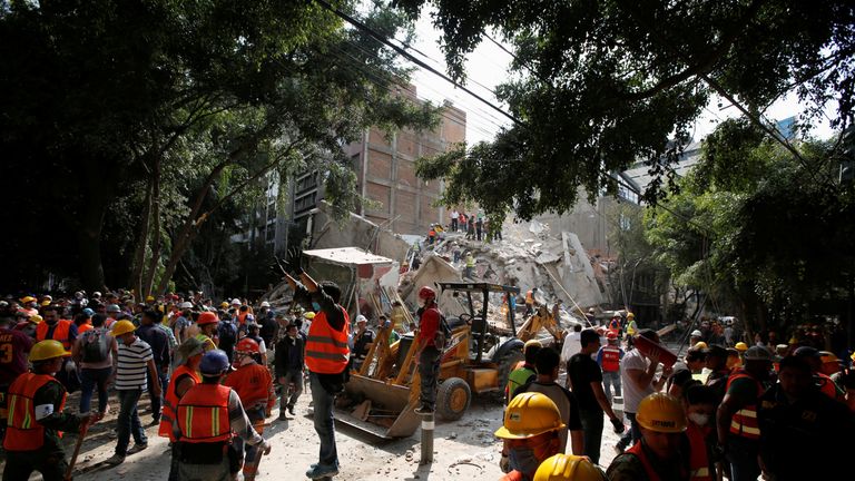 A man motions for everybody to be quiet as rescue workers look for people under the rubble 